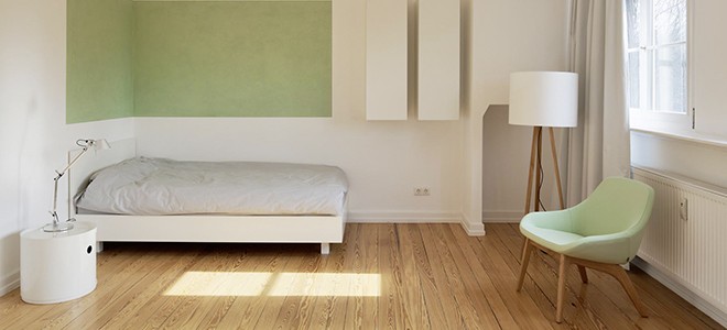 Eine Wand mit Bett, Lampe und Stuhl