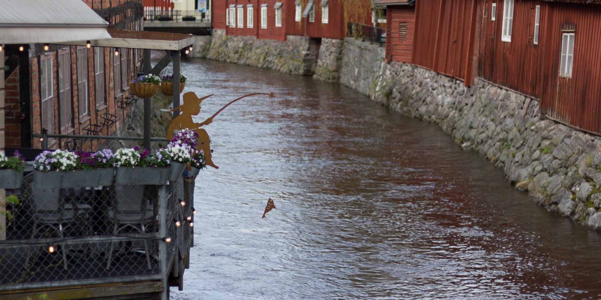 Enger Fluss mit Häusern am Ufer in Schweden