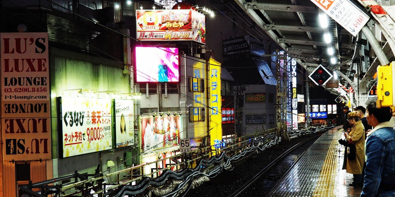 Menschen stehen an einer Bahnhaltestelle in Asien