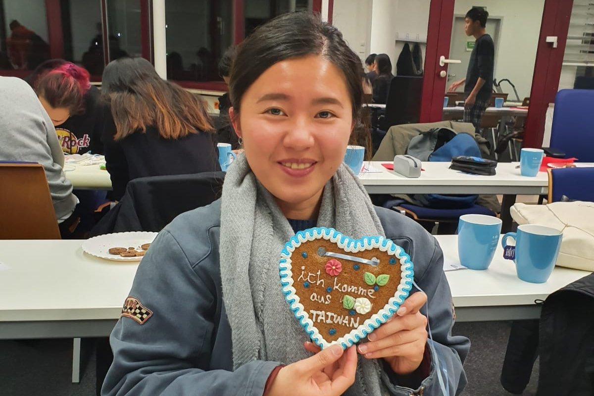 A Student is holding up a self-made German ginger-bread cookie