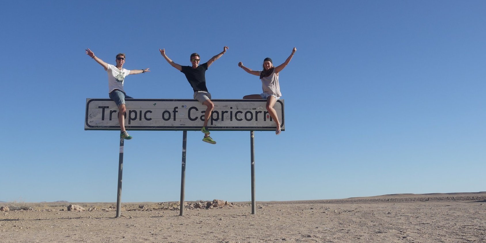 Students sitting on top of a sign saying Tropic de Capricorn