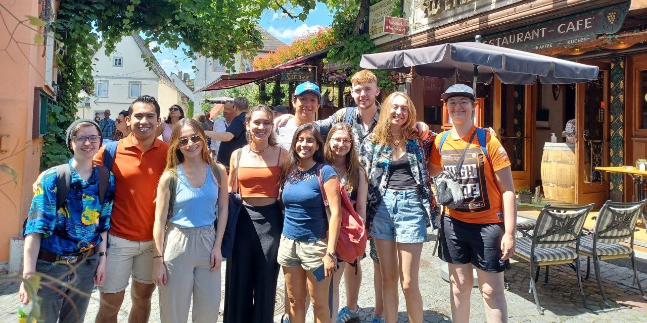 A group of students is standing in a little alleyway in Ruedesheim