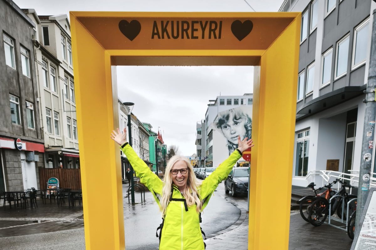 Eine Mitarbeiterin des International Offices steht in Akureyri vor einem großen Fotobilderrahmen in der Innenstadt