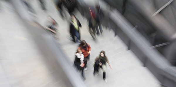 Verschwommene Aufnahme mehrerer Studierender, die zwischen zwei Gebäude entlanglaufen