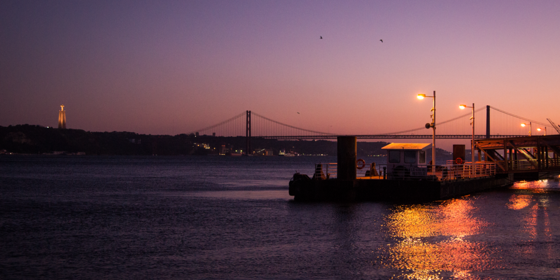 A sunset over a bridge in Lisbon, Portugal